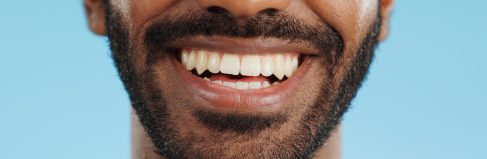 smile-closeup-and-black-man-with-teeth-in-studio-2025-04-05-18-37-24-utc Smile, closeup and black man with teeth in studio, blue background and mockup space with happiness .